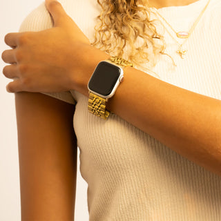 Person wearing a gold smartwatch on a plain background