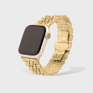 Gold watch with a metallic band on a light gray background