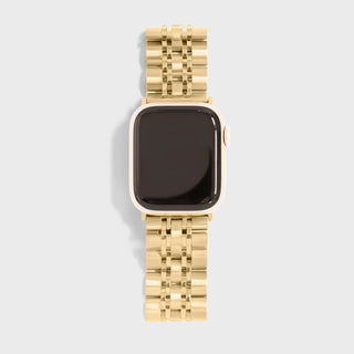 Gold watch with a patterned band on a light gray background