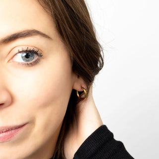 Close-up of a woman wearing a gold earring on a white background