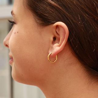 Close-up of a person wearing a gold hoop earring.