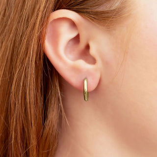 Gold hoop earring worn by a person with red hair