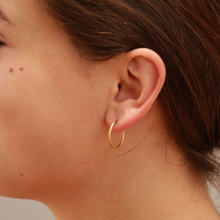 Close-up of a person wearing a gold hoop earring.