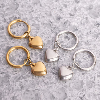 Gold and silver heart-shaped keychains on a textured gray surface