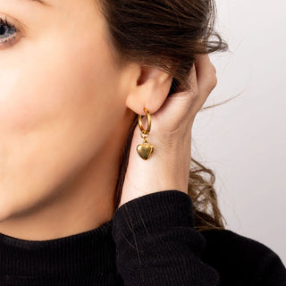 Close-up of a person wearing a gold heart-shaped earring.