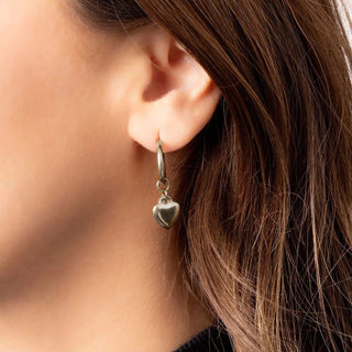 Close-up of an ear wearing a heart-shaped earring with blurred background