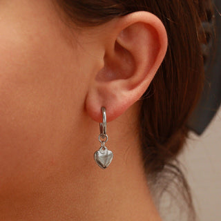 Close-up of an ear wearing a silver heart-shaped earring.