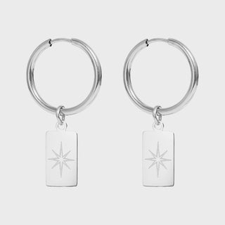 Silver hoop earrings with engraved star charms on a light gray background