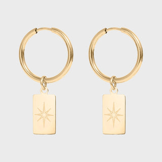 Gold hoop earrings with star-shaped charms on a light gray background