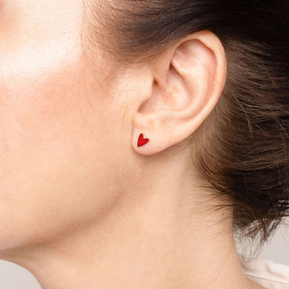 Close-up of an ear wearing a red heart-shaped earring.