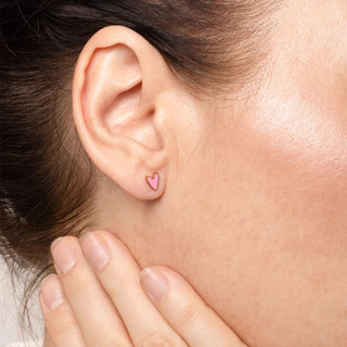 Close-up of an ear with a pink heart-shaped earring.