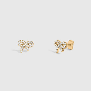 Gold bow-shaped earrings with clear stones on a light gray background