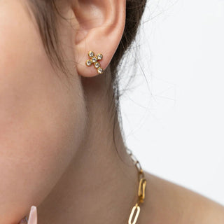 Close-up of a person wearing gold earrings with a blurred background