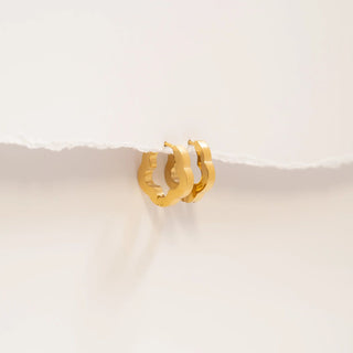 Gold hoop earrings on a light beige background