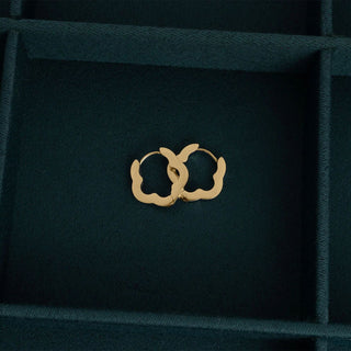 Gold hoop earrings on a dark green jewelry box