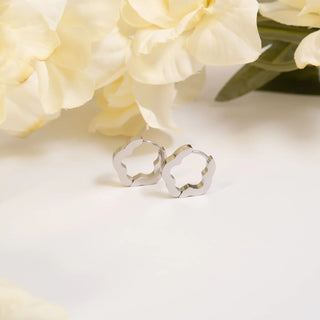 Silver earrings on a white surface with yellow flowers in the background
