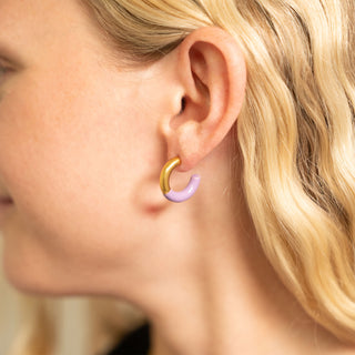 Close-up of a person wearing a gold and purple hoop earring.