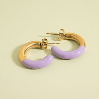 Gold and purple hoop earrings on a beige background