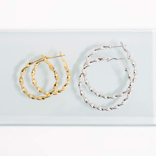 Gold and silver hoop earrings on a light blue background