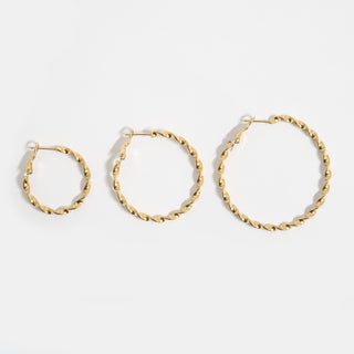 Three gold hoop earrings of different sizes on a white background