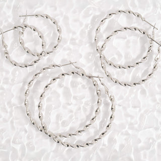 Set of silver hoop earrings on a textured white background