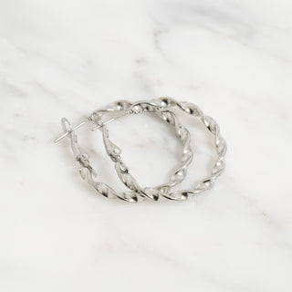 Silver hoop earrings on a white marble surface
