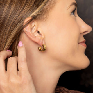 Woman wearing gold hoop earrings with a blurred background