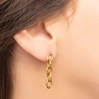 Gold chain earring worn by a person with a neutral background