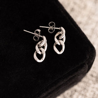 Silver chain link earrings on a black surface