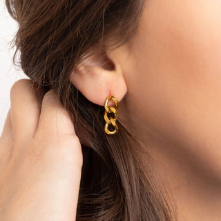 Gold chain earring worn by a person with brown hair.
