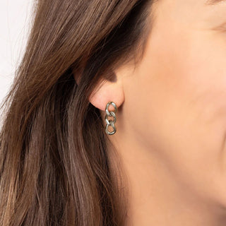Close-up of a person wearing silver chain earrings with a neutral background