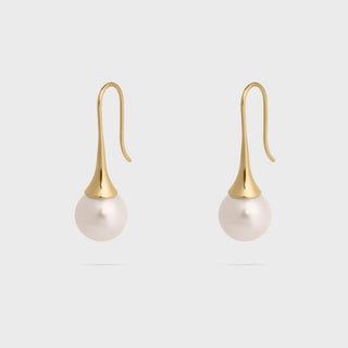 Pair of pearl earrings with gold hooks on a light gray background