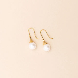 Gold earrings with pearl drops on a beige background