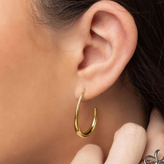 Gold hoop earring worn by a person with a blurred background
