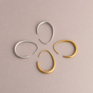 Two pairs of hoop earrings, one silver and one gold, on a beige background.