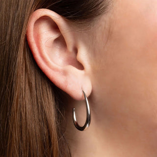 Close-up of an ear wearing a silver hoop earring with blurred background