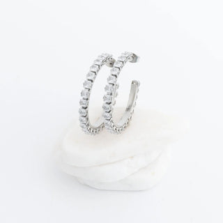 Silver hoop earrings with clear gemstones on a white background