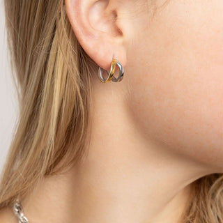 Close-up of a person wearing a gold and silver hoop earring.