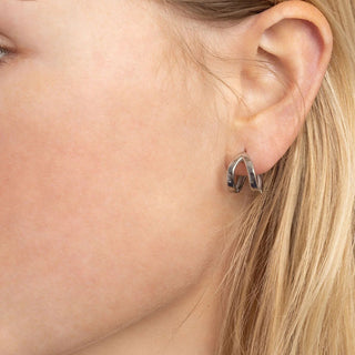 Close-up of a person wearing a silver hoop earring.