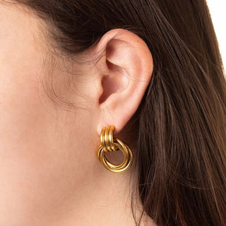 Gold hoop earring worn by a person with dark hair.