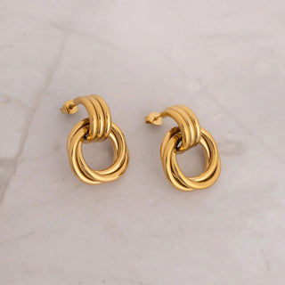 Pair of gold hoop earrings on a light marble background