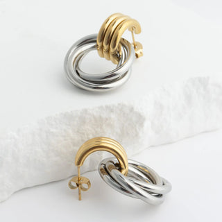 Pair of gold and silver hoop earrings on a white surface