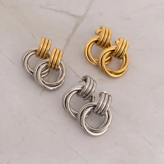 Pair of gold and silver hoop earrings on a light gray background