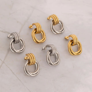 Pair of gold and silver hoop earrings on a light gray background