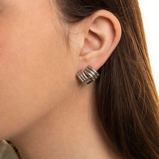 Close-up of an ear wearing a silver earring with a neutral background