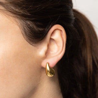 Gold earring worn by a person with dark hair.