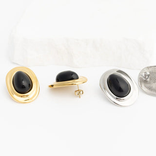 Pair of black stone Black Enamel Stud Earrings with gold and silver metal backs on a white background