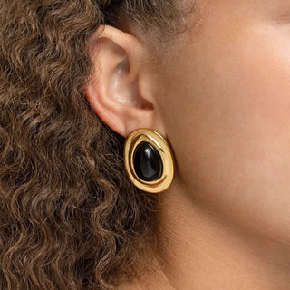 Gold Black Enamel Stud Earrings with a black stone worn by a person with curly hair.