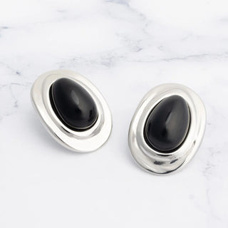 Pair of silver Black Enamel Stud Earrings with black stones on a marble surface