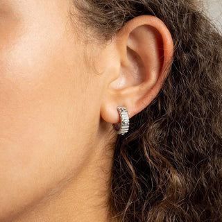 Close-up of an ear wearing a silver hoop earring with hair partially covering the side of the face.